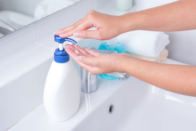 Close-up of person hand holding bottle in bathroom