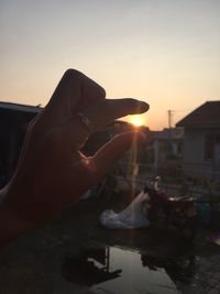 Close-up of woman hand holding sun against sky during sunset