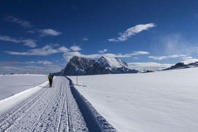 Woman walking on snowy land against snowcapped mountains