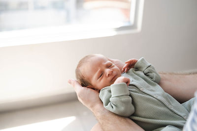 Close up of caucasian hairy brunet cute newborn baby sleeping in male hands