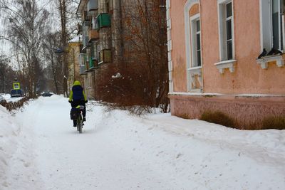 Rear view of person riding motorcycle on street during winter