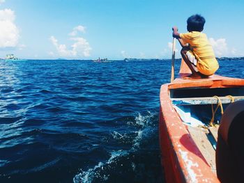 Rear view of boy sailing boat in sea