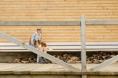 Woman sitting on a wooden bench with her dog on her lap