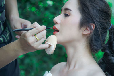 Close-up of person applying make-up on woman face