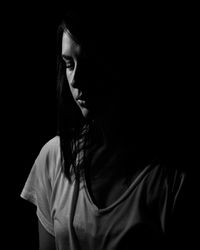 Close-up of young woman standing against black background