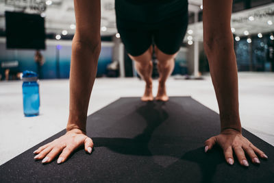 Low section of young woman exercising on mat with mobile phone at gym