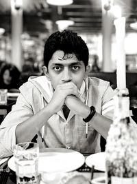 Portrait of young man sitting on table in restaurant