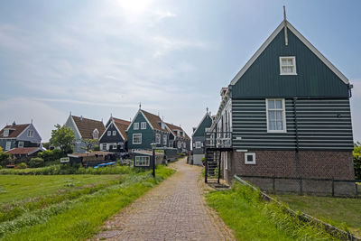 Footpath amidst houses on field against sky