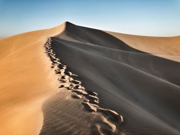 Sand dunes in desert against clear sky