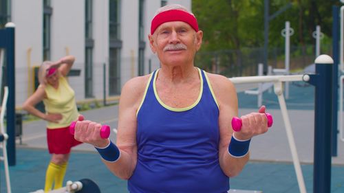 Senior man holding dumbbells at park