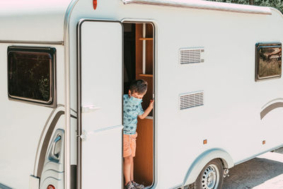 Rear view of boy standing on car