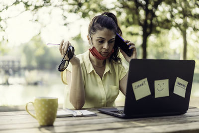 Woman using phone while sitting on table