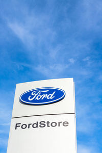 Low angle view of road sign against blue sky