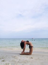 Woman standing at beach against sky