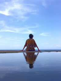 Rear view of man looking at sea against sky