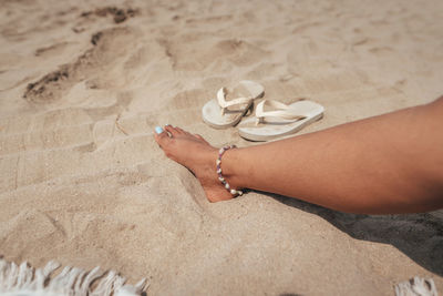 Low section of woman standing on sand at beach