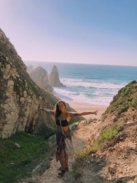 Woman standing on sea shore against sky