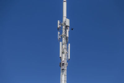 Low angle view of communications tower against clear blue sky