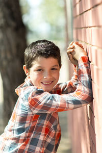 Portrait of smiling boy standing against brick wall