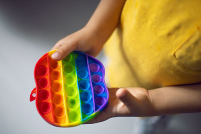 Boy in a yellow t-shirt plays a fashion game pop it in the form of a silicone apple