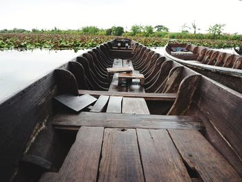 Empty seats by lake against sky