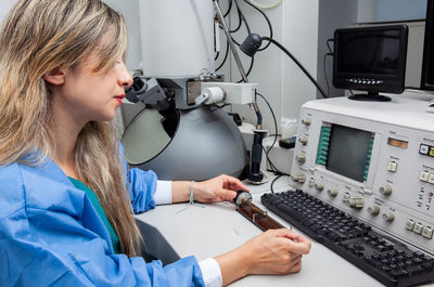 Female scientist loading a grid with an specimen on the sample holder of an electron microscope