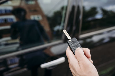 Hand of man unlocking car using key