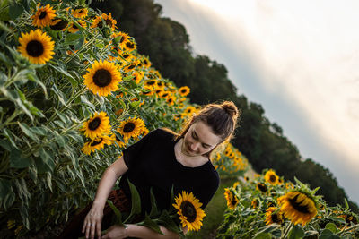 Young woman holding sunflower while standing outdoors