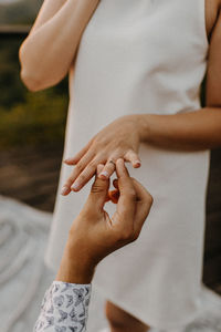 Cropped hand putting ring in woman hand outdoors