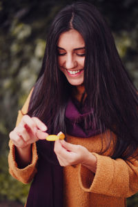 Close-up of young woman holding flower while standing in forest during winter