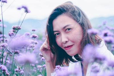 Portrait of smiling woman against purple flowering plants