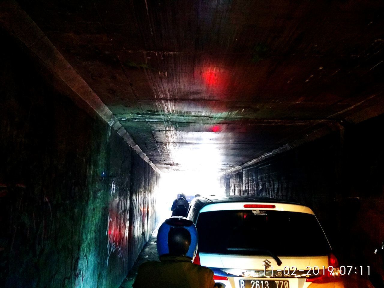 REAR VIEW OF MAN PHOTOGRAPHING ILLUMINATED TUNNEL