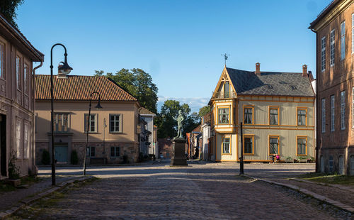 Street by houses against clear sky