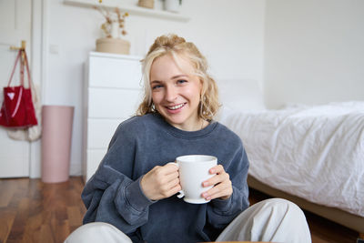 Young woman using mobile phone while sitting on sofa at home