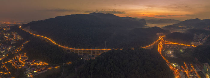 Aerial view of illuminated mountain against sky at sunset