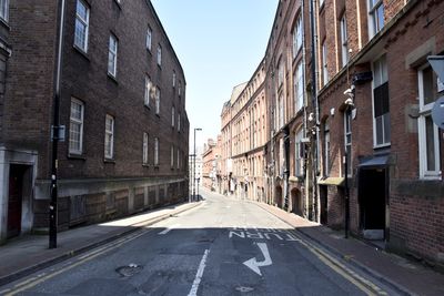 Empty road amidst buildings against clear sky