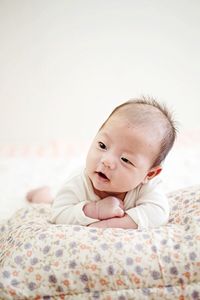 Portrait of cute baby girl lying on bed