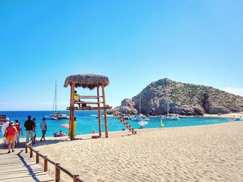 People at beach against clear blue sky