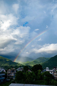 Rainbow over buildings in city against sky