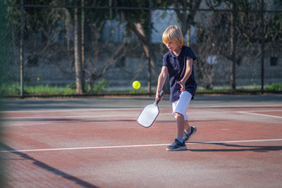 Full length of boy playing tennis