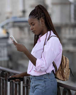 Profile view of young afro american tourist woman using smart phone on street in madrid city