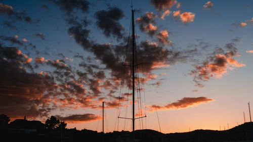 Low angle view of silhouette electricity pylon against dramatic sky