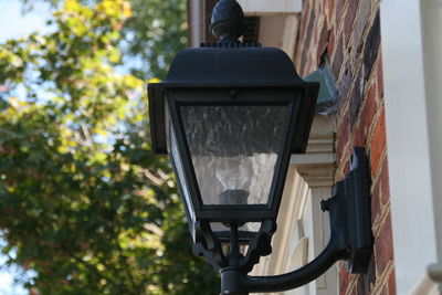 Low angle view of electric lamp against trees