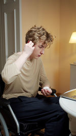 Young man sitting on wheelchair at home