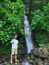 Man standing by waterfall in forest