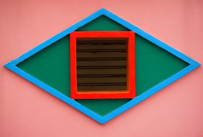 Close-up of small window on pink wall