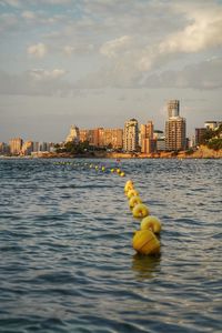 Yellow floating on sea against buildings in city