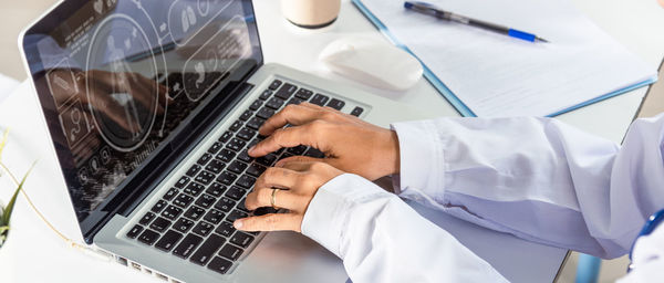 Midsection of doctor using laptop