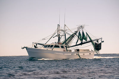 Shrimpboat sailing on sea against clear sky