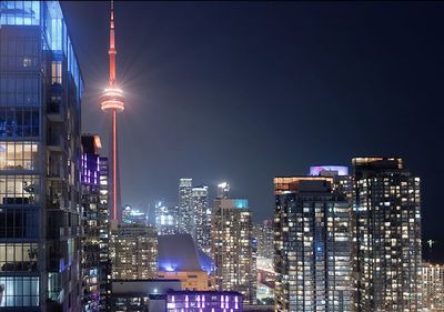 Illuminated buildings in city against sky at night